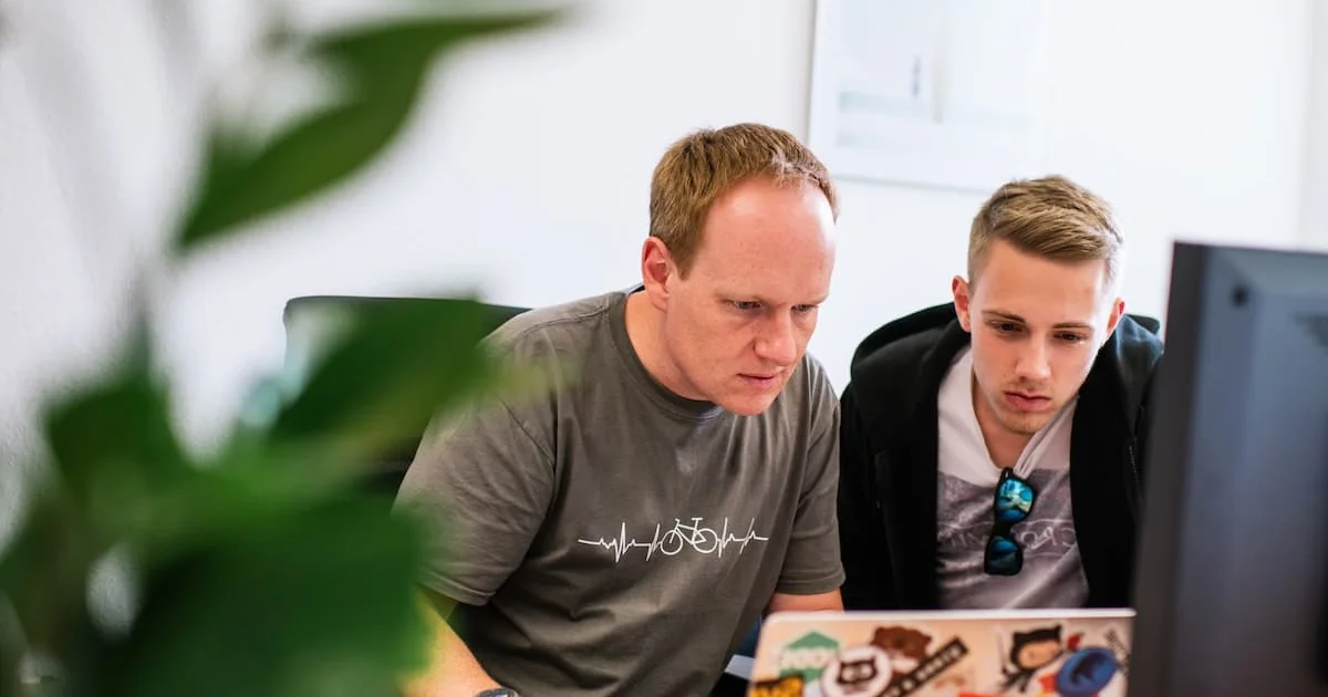 Zwei Softwareentwickler schauen gespannt auf einen Laptop