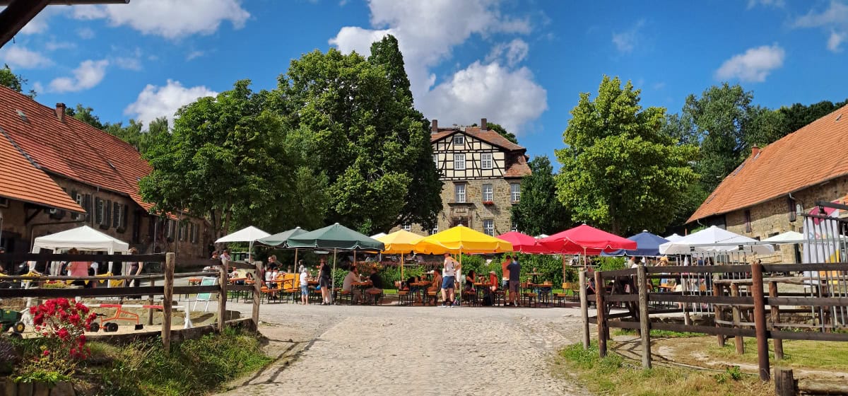 Micromata-Sommerfest 2025 auf Gut Waitzrodt: Panoramablick auf Innenhof mit bunten Sonnenschirmen