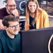 Ein Team von Micromata-Softwareentwickelnden gruppiert sich lachend um einen Monitor