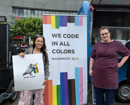 Micromata-Aufsteller mit der Aufschrift WE CODE IN ALL COLORS neben dem Eiswagen von Frohnatur, rechts und links zwei Frauen.